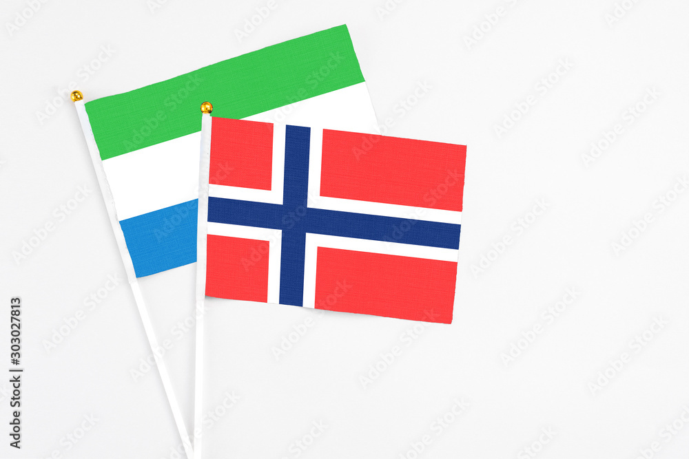 Obraz premium Bouvet Islands and Sierra Leone stick flags on white background. High quality fabric, miniature national flag. Peaceful global concept.White floor for copy space.