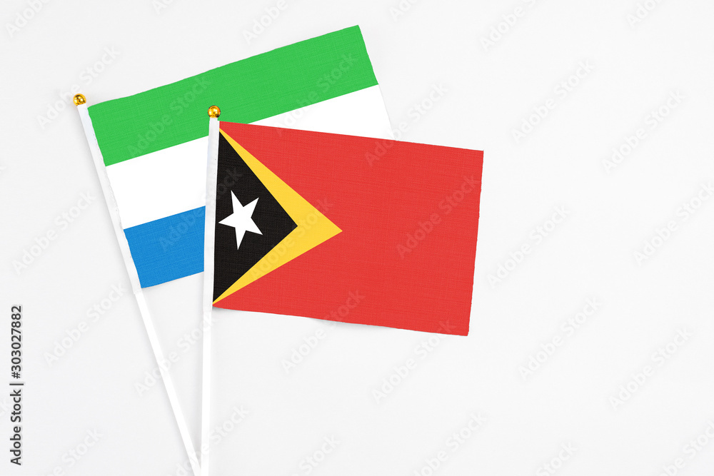 East Timor and Sierra Leone stick flags on white background. High quality fabric, miniature national flag. Peaceful global concept.White floor for copy space. East Timor and Sierra Leone stick flags on white background. High quality fabric, miniature national flag. Peaceful global concept.White floor for copy space.