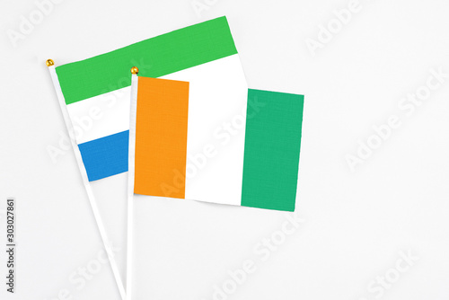 Cote D'Ivoire and Sierra Leone stick flags on white background. High quality fabric, miniature national flag. Peaceful global concept.White floor for copy space.