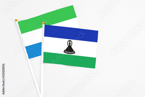 Lesotho and Sierra Leone stick flags on white background. High quality fabric, miniature national flag. Peaceful global concept.White floor for copy space.