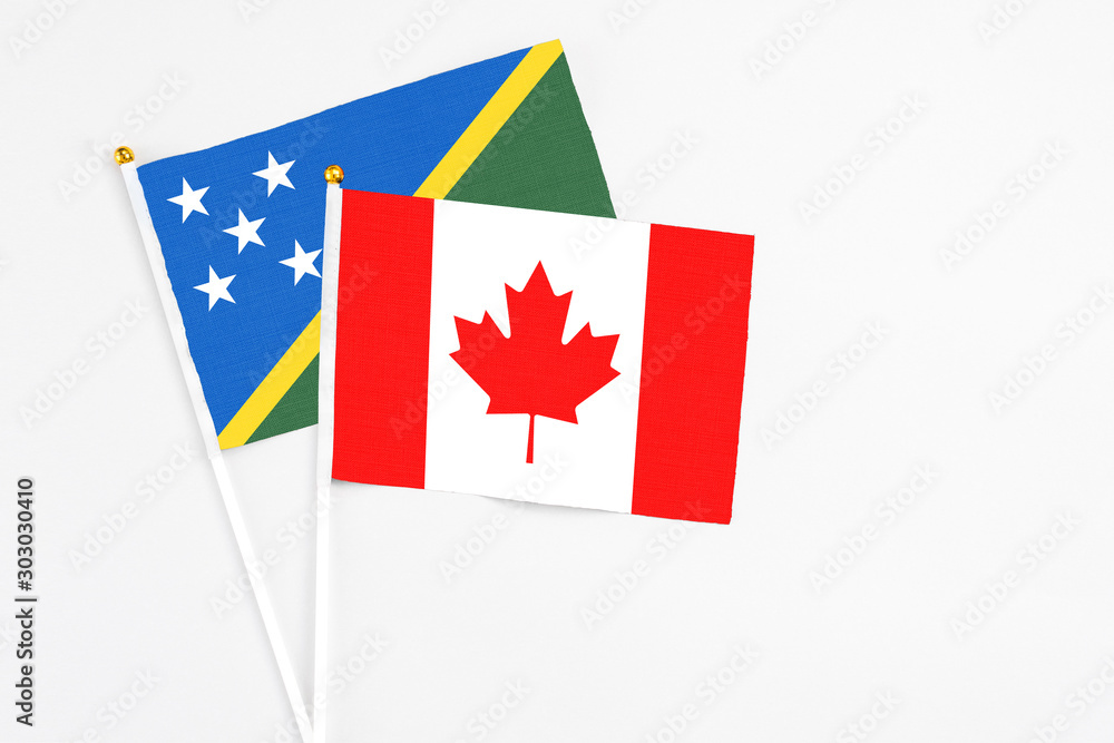 Canada and Solomon Islands stick flags on white background. High quality fabric, miniature national flag. Peaceful global concept.White floor for copy space. Canada and Solomon Islands stick flags on white background. High quality fabric, miniature national flag. Peaceful global concept.White floor for copy space.