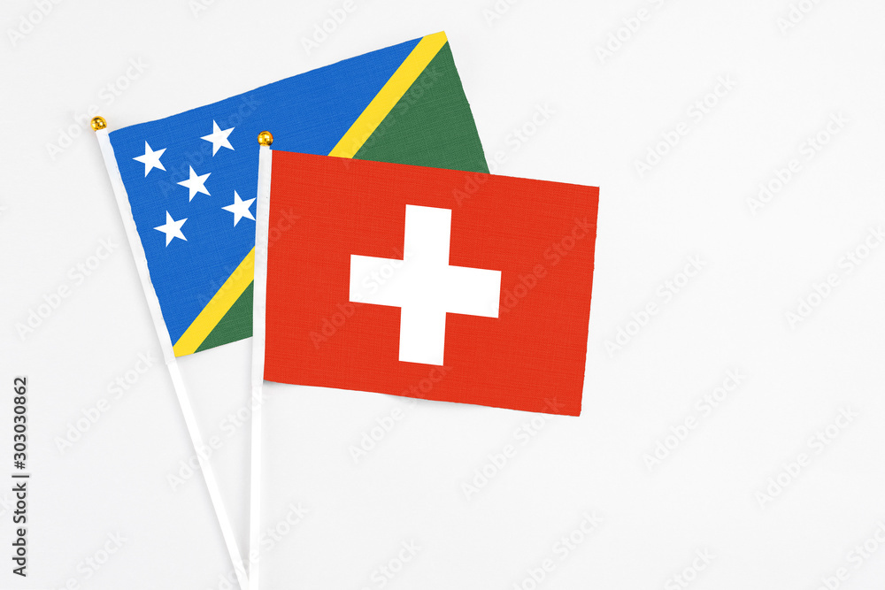 Switzerland and Solomon Islands stick flags on white background. High quality fabric, miniature national flag. Peaceful global concept.White floor for copy space.