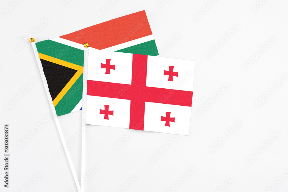 Georgia and South Africa stick flags on white background. High quality fabric, miniature national flag. Peaceful global concept.White floor for copy space.
