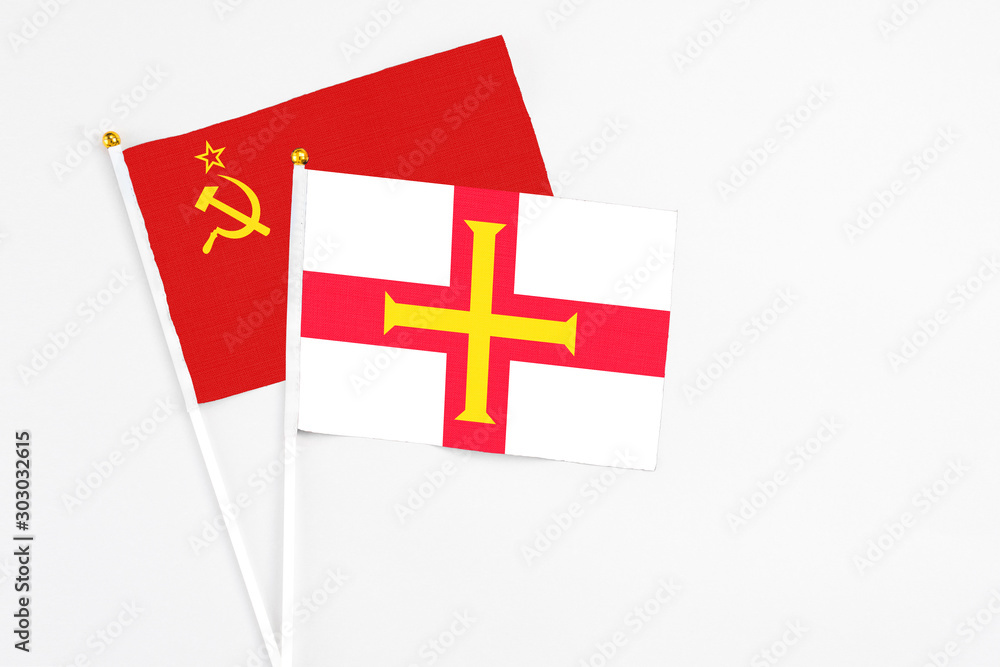 Guernsey and Soviet Union stick flags on white background. High quality fabric, miniature national flag. Peaceful global concept.White floor for copy space.