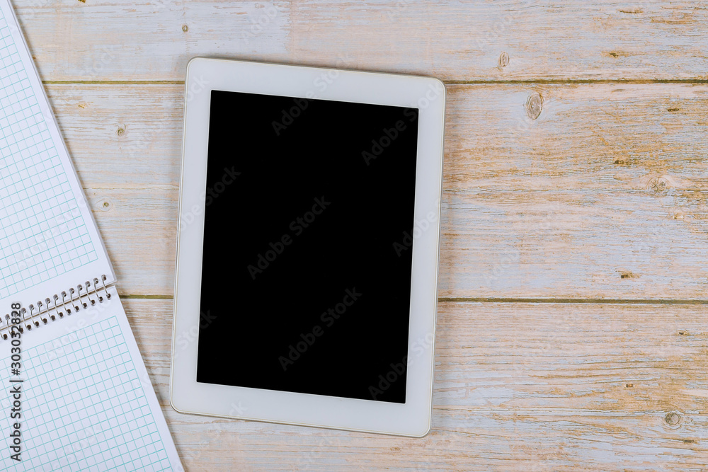 Workspace desk with paper notebook on table touch screen device with copy space background Workspace desk with paper notebook on table touch screen device with copy space background