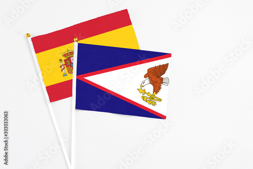 American Samoa and Spain stick flags on white background. High quality fabric  miniature national flag. Peaceful global concept.White floor for copy space.