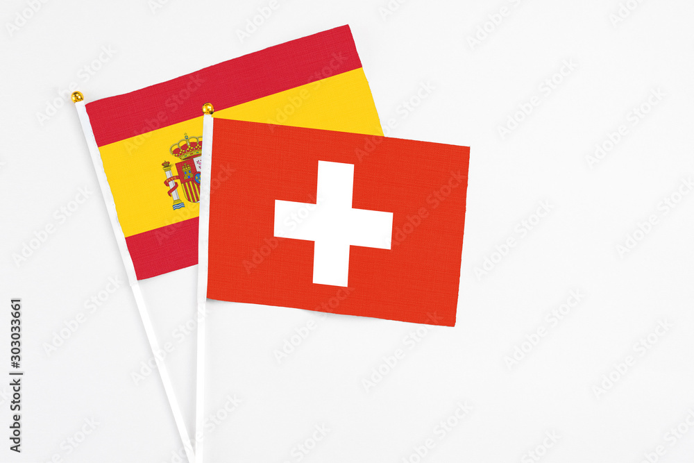 Switzerland and Spain stick flags on white background. High quality fabric, miniature national flag. Peaceful global concept.White floor for copy space.