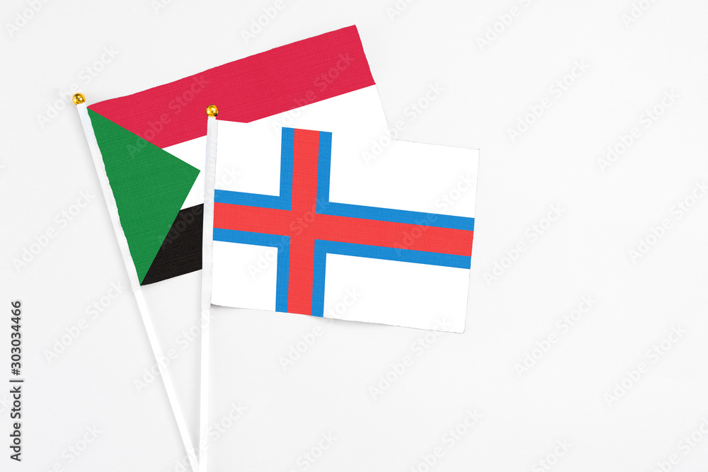 Faroe Islands and Sudan stick flags on white background. High quality fabric, miniature national flag. Peaceful global concept.White floor for copy space.