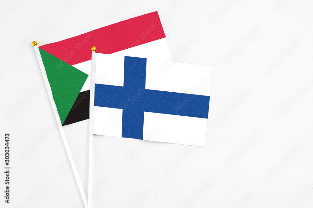 Finland and Sudan stick flags on white background. High quality fabric, miniature national flag. Peaceful global concept.White floor for copy space.