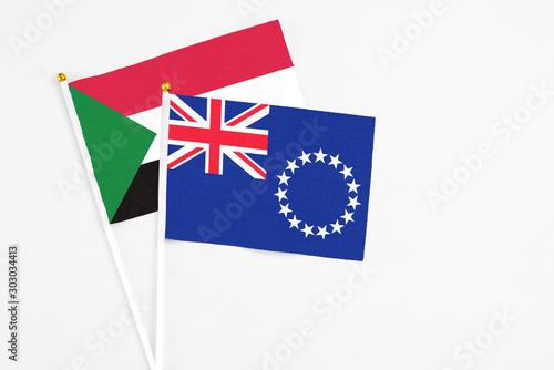 Cook Islands and Sudan stick flags on white background. High quality fabric, miniature national flag. Peaceful global concept.White floor for copy space.