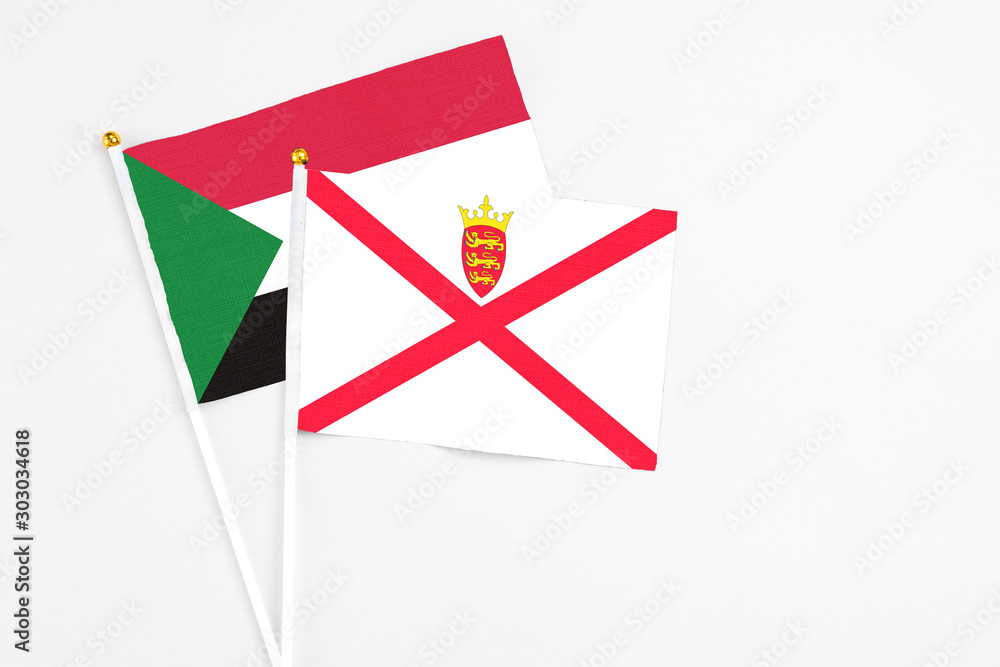 Jersey and Sudan stick flags on white background. High quality fabric, miniature national flag. Peaceful global concept.White floor for copy space. Jersey and Sudan stick flags on white background. High quality fabric, miniature national flag. Peaceful global concept.White floor for copy space.