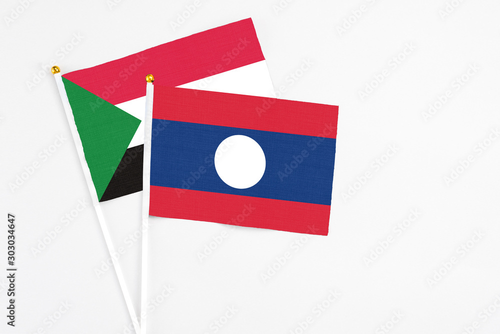 Laos and Sudan stick flags on white background. High quality fabric, miniature national flag. Peaceful global concept.White floor for copy space. Laos and Sudan stick flags on white background. High quality fabric, miniature national flag. Peaceful global concept.White floor for copy space.