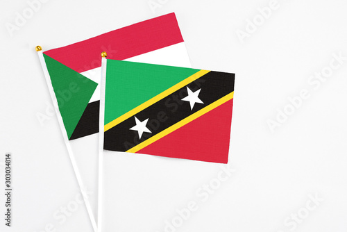 Free Download Saint Kitts And Nevis and Sudan stick flags on white background. High quality fabric, miniature national flag. Peaceful global concept.White floor for copy space. - GFXLoad
