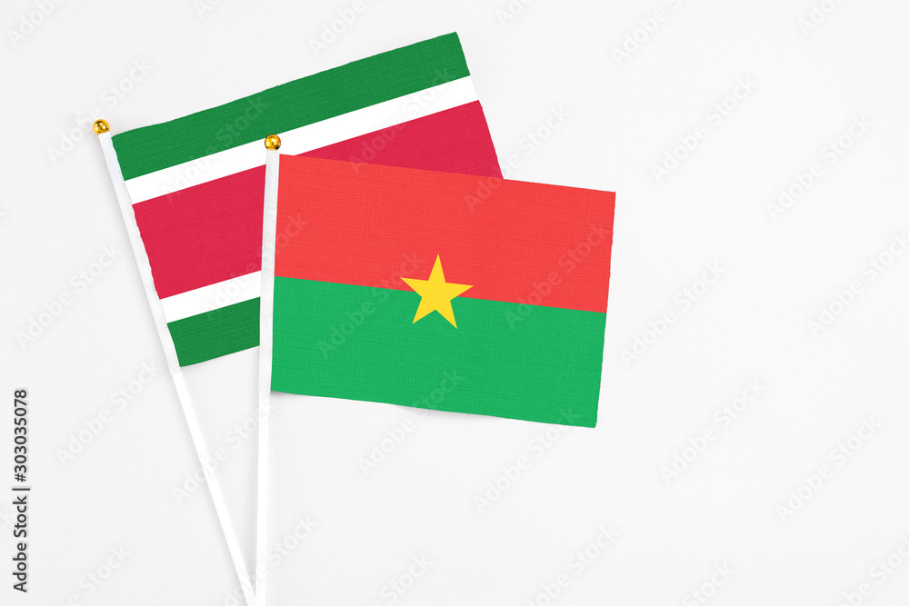 Burkina Faso and Suriname stick flags on white background. High quality fabric, miniature national flag. Peaceful global concept.White floor for copy space. Burkina Faso and Suriname stick flags on white background. High quality fabric, miniature national flag. Peaceful global concept.White floor for copy space.
