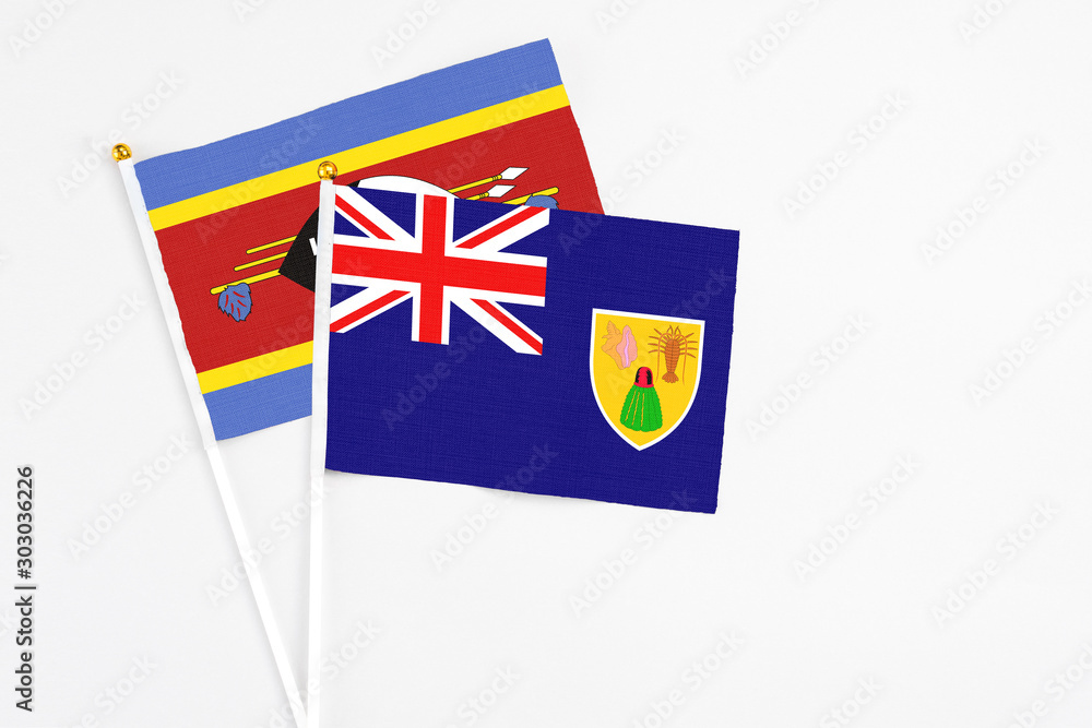 Fototapeta premium Turks And Caicos Islands and Swaziland stick flags on white background. High quality fabric, miniature national flag. Peaceful global concept.White floor for copy space.