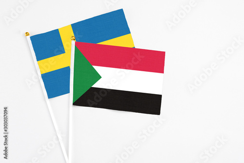 Sudan and Sweden stick flags on white background. High quality fabric, miniature national flag. Peaceful global concept.White floor for copy space.