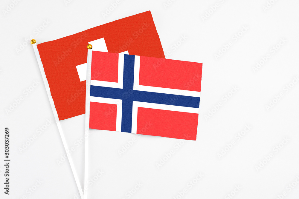 Bouvet Islands and Switzerland stick flags on white background. High quality fabric, miniature national flag. Peaceful global concept.White floor for copy space.
