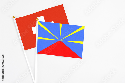 Reunion and Switzerland stick flags on white background. High quality fabric, miniature national flag. Peaceful global concept.White floor for copy space.
