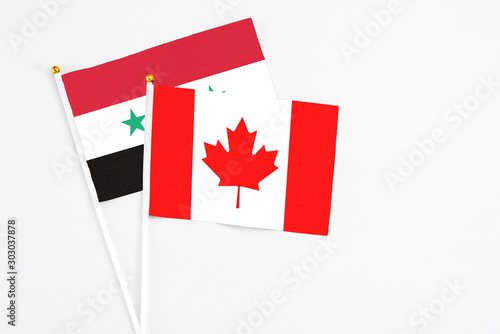 Canada and Syria stick flags on white background. High quality fabric, miniature national flag. Peaceful global concept.White floor for copy space.