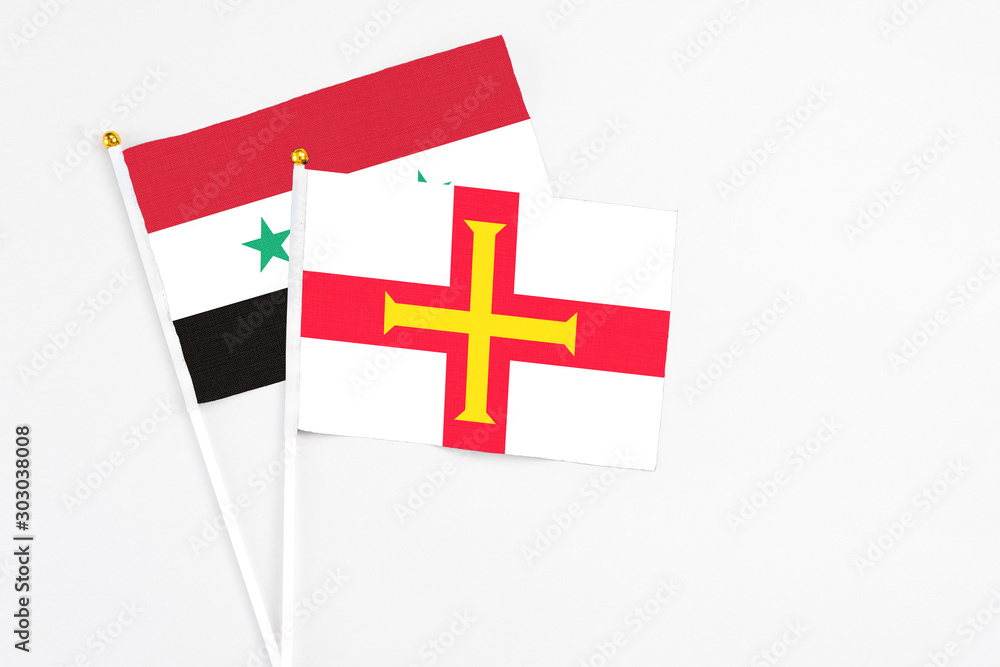 Guernsey and Syria stick flags on white background. High quality fabric, miniature national flag. Peaceful global concept.White floor for copy space.