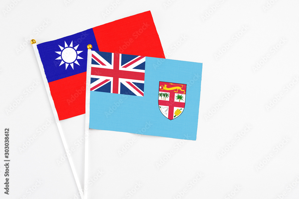 Fototapeta premium Fiji and Taiwan stick flags on white background. High quality fabric, miniature national flag. Peaceful global concept.White floor for copy space.