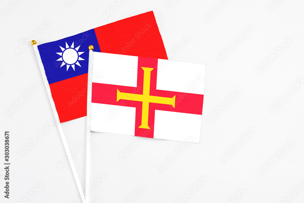 Guernsey and Taiwan stick flags on white background. High quality fabric, miniature national flag. Peaceful global concept.White floor for copy space.