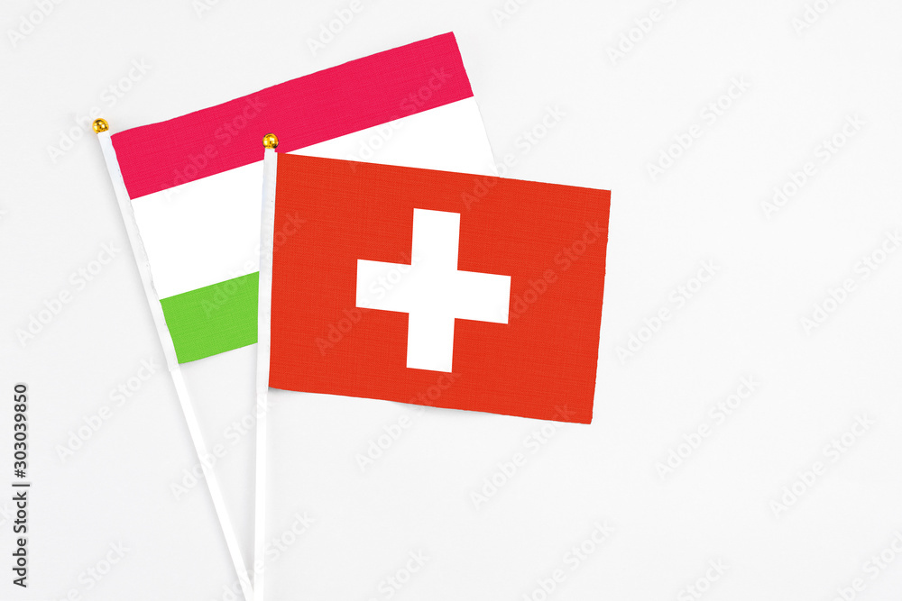 Switzerland and Tajikistan stick flags on white background. High quality fabric, miniature national flag. Peaceful global concept.White floor for copy space.