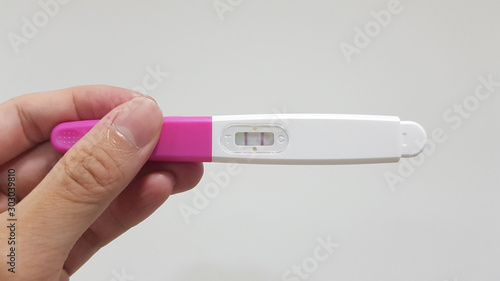 Hand holding pregnancy test with positive result (pregnant). Pregnancy or gestation can occur by sexual intercourse or assisted reproductive technology (ART). Family planning and health care concept 