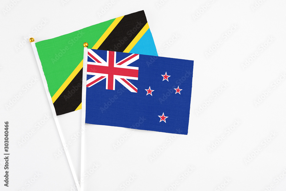 Fototapeta premium New Zealand and Tanzania stick flags on white background. High quality fabric, miniature national flag. Peaceful global concept.White floor for copy space.