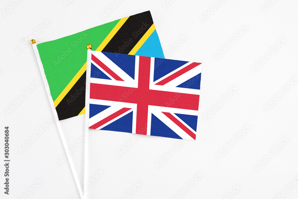 Fototapeta premium United Kingdom and Tanzania stick flags on white background. High quality fabric, miniature national flag. Peaceful global concept.White floor for copy space.