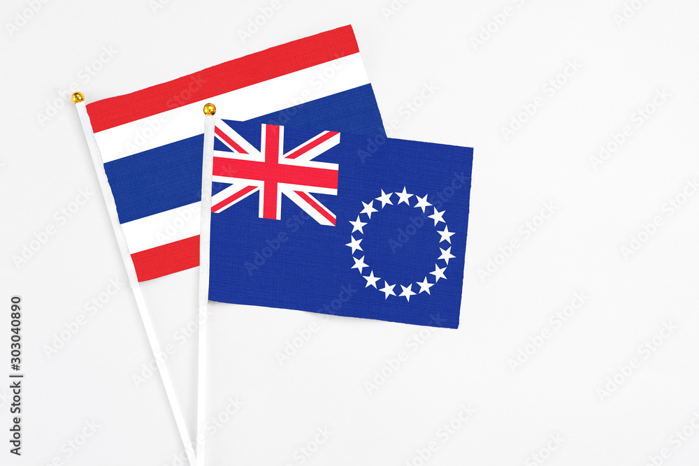Fototapeta premium Cook Islands and Thailand stick flags on white background. High quality fabric, miniature national flag. Peaceful global concept.White floor for copy space.