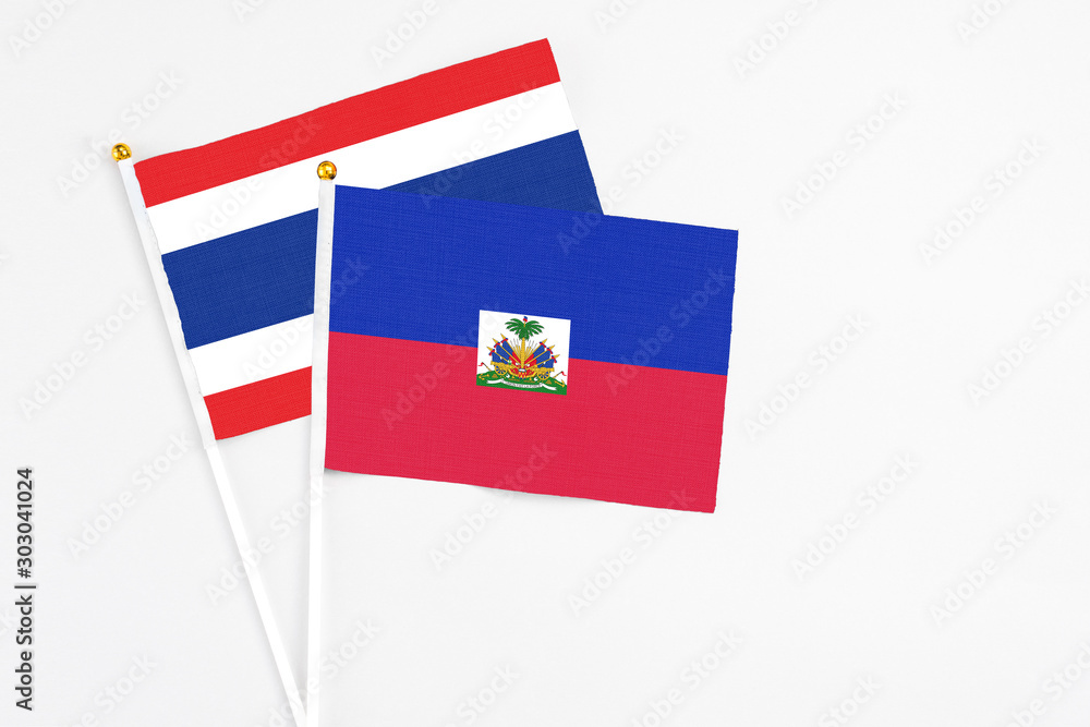 Obraz premium Haiti and Thailand stick flags on white background. High quality fabric, miniature national flag. Peaceful global concept.White floor for copy space.