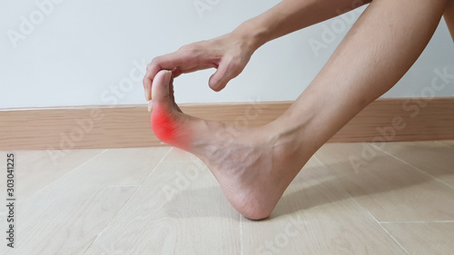 Hand holding on foot anatomy with red highlight on painful area. Toe pain may cause from bone fracture, tendinitis, ligament sprain, gout arthritis or bunion disease. medical symptom photo