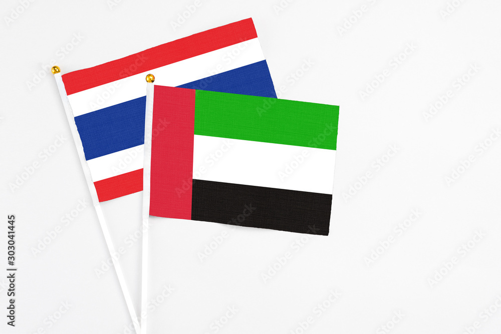 United Arab Emirates and Thailand stick flags on white background. High quality fabric, miniature national flag. Peaceful global concept.White floor for copy space. United Arab Emirates and Thailand stick flags on white background. High quality fabric, miniature national flag. Peaceful global concept.White floor for copy space.