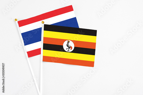 Free Download Uganda and Thailand stick flags on white background. High quality fabric, miniature national flag. Peaceful global concept.White floor for copy space. - GFXLoad