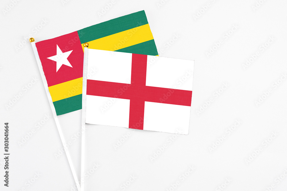 England and Togo stick flags on white background. High quality fabric, miniature national flag. Peaceful global concept.White floor for copy space.