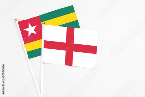England and Togo stick flags on white background. High quality fabric, miniature national flag. Peaceful global concept.White floor for copy space.