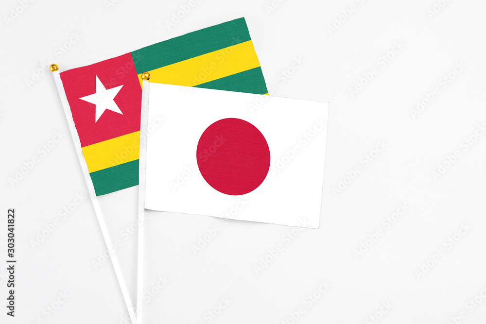 Japan and Togo stick flags on white background. High quality fabric, miniature national flag. Peaceful global concept.White floor for copy space.