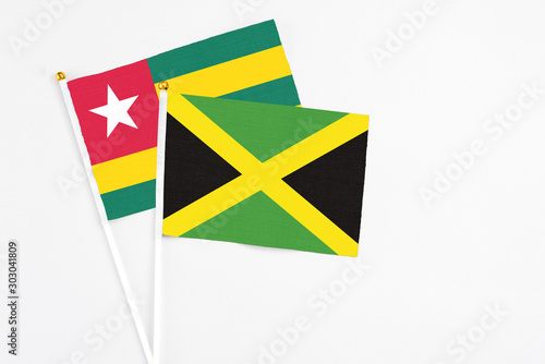 Jamaica and Togo stick flags on white background. High quality fabric, miniature national flag. Peaceful global concept.White floor for copy space. photo