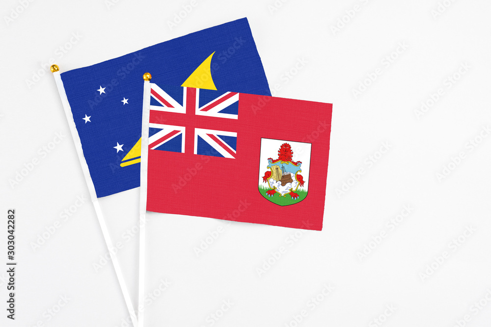 Fototapeta premium Bermuda and Tokelau stick flags on white background. High quality fabric, miniature national flag. Peaceful global concept.White floor for copy space.