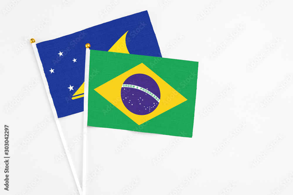 Brazil and Tokelau stick flags on white background. High quality fabric, miniature national flag. Peaceful global concept.White floor for copy space.