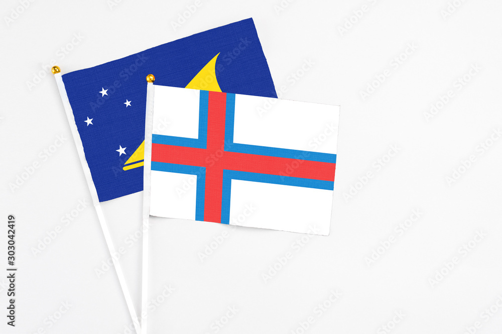 Faroe Islands and Tokelau stick flags on white background. High quality fabric, miniature national flag. Peaceful global concept.White floor for copy space.