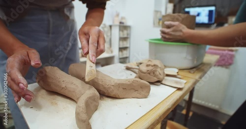 Close up of female hands performing clay form on pottery table with instruments. Handmade art object. Successful freelance educating lifestyle. Creative classroom for craft training. Adult educating. photo