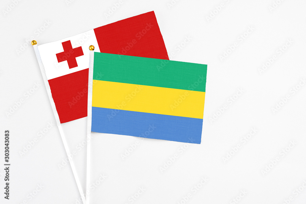 Gabon and Tonga stick flags on white background. High quality fabric, miniature national flag. Peaceful global concept.White floor for copy space. Gabon and Tonga stick flags on white background. High quality fabric, miniature national flag. Peaceful global concept.White floor for copy space.