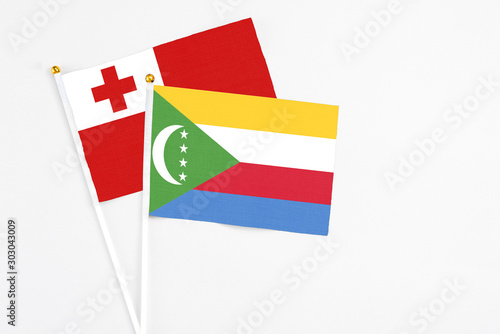 Comoros and Tonga stick flags on white background. High quality fabric, miniature national flag. Peaceful global concept.White floor for copy space. photo