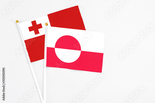 Greenland and Tonga stick flags on white background. High quality fabric, miniature national flag. Peaceful global concept.White floor for copy space. photo