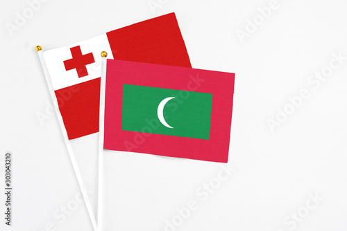 Maldives and Tonga stick flags on white background. High quality fabric, miniature national flag. Peaceful global concept.White floor for copy space.