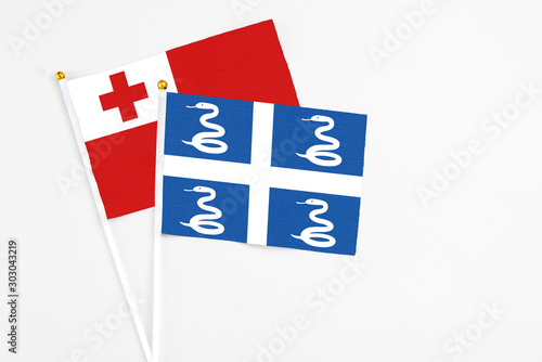 Martinique and Tonga stick flags on white background. High quality fabric, miniature national flag. Peaceful global concept.White floor for copy space. photo