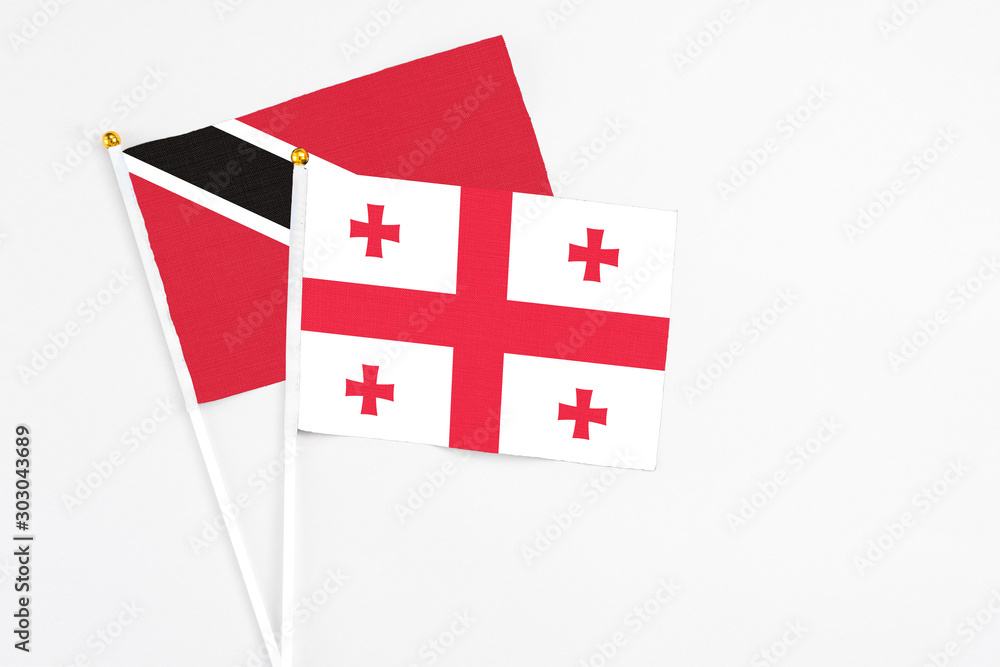 Georgia and Trinidad And Tobago stick flags on white background. High quality fabric, miniature national flag. Peaceful global concept.White floor for copy space.