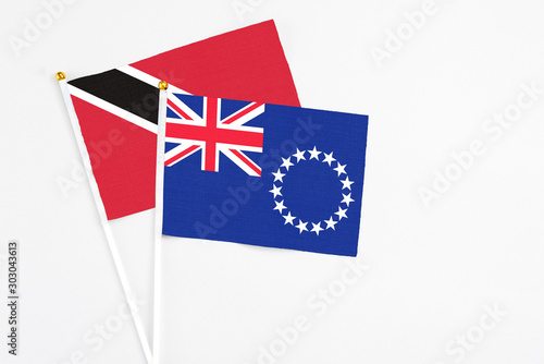 Cook Islands and Trinidad And Tobago stick flags on white background. High quality fabric, miniature national flag. Peaceful global concept.White floor for copy space.